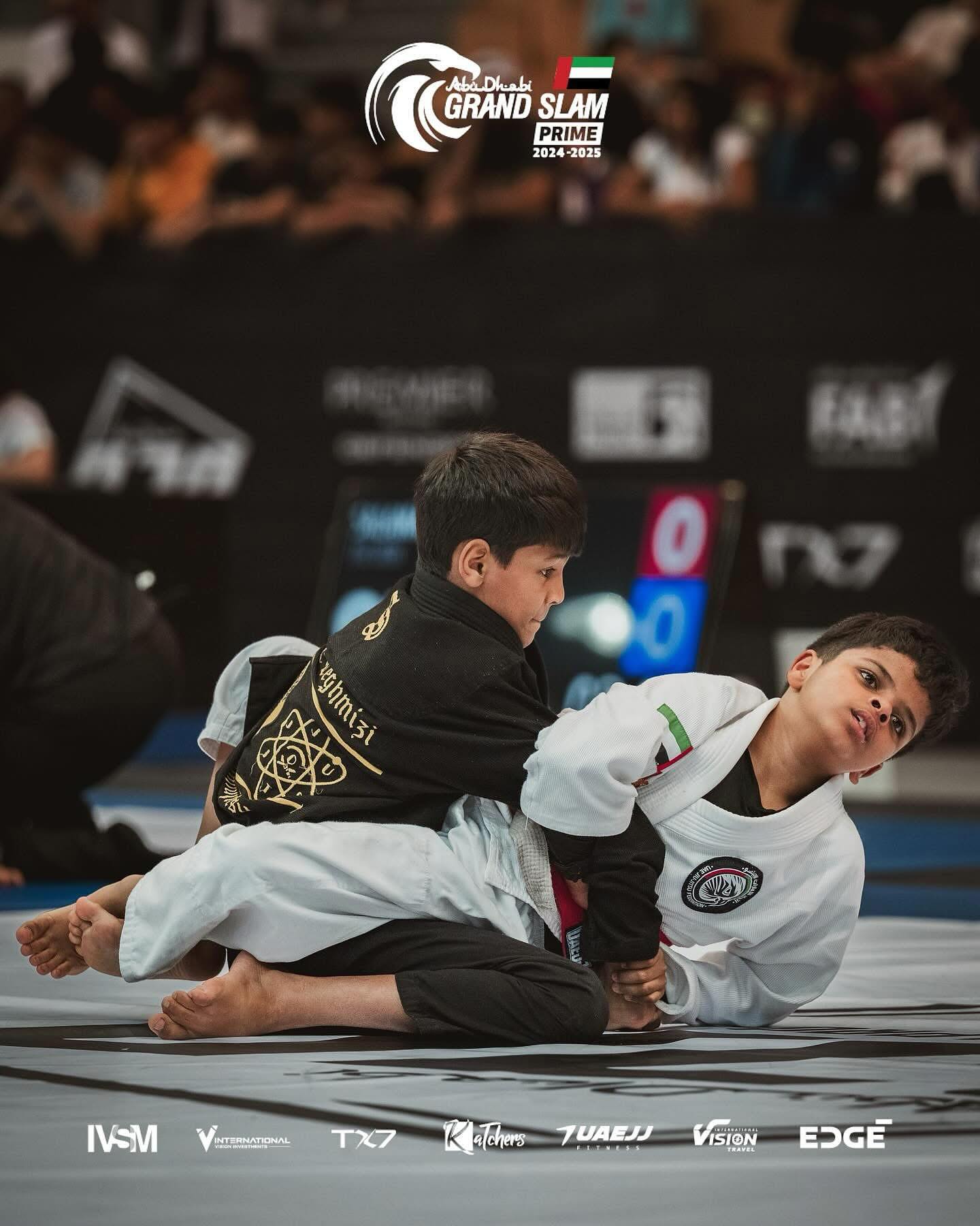 atom-kids-grand-slam-2025 Our young athlete Ishaq competing in the Abu Dhabi Grand Slam 2025, wearing black gi uniforms, in an intense Jiu Jitsu match.